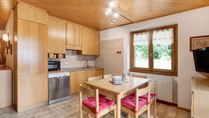 A kitchen with wooden cabinets, a microwave, a sink, and a dining table with chairs. - Apartment 'Chalet Holly' with Mountain View, Shared Garden and Wi-Fi (Bormio)