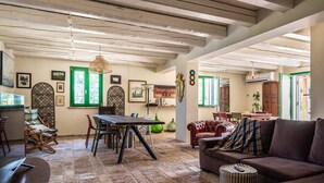 A rustic interior with exposed wooden beams, a dining area with a wooden table and chairs, a leather sofa, and a patterned rug. - Villa 'All'ombra Della Quercia' with Private Pool, Wi-Fi and Air Conditioning (Fano)