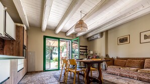 A kitchen with wooden cabinets, a dining table with chairs, a hanging light fixture, and a sofa. - Villa 'All'ombra Della Quercia' with Private Pool, Wi-Fi and Air Conditioning (Fano)
