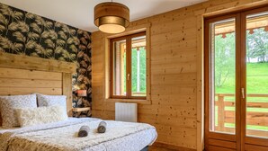 Ein Zimmer mit Holzboden, einem Bett, einer Heizung und einem Fenster mit Blick auf eine Wiese.