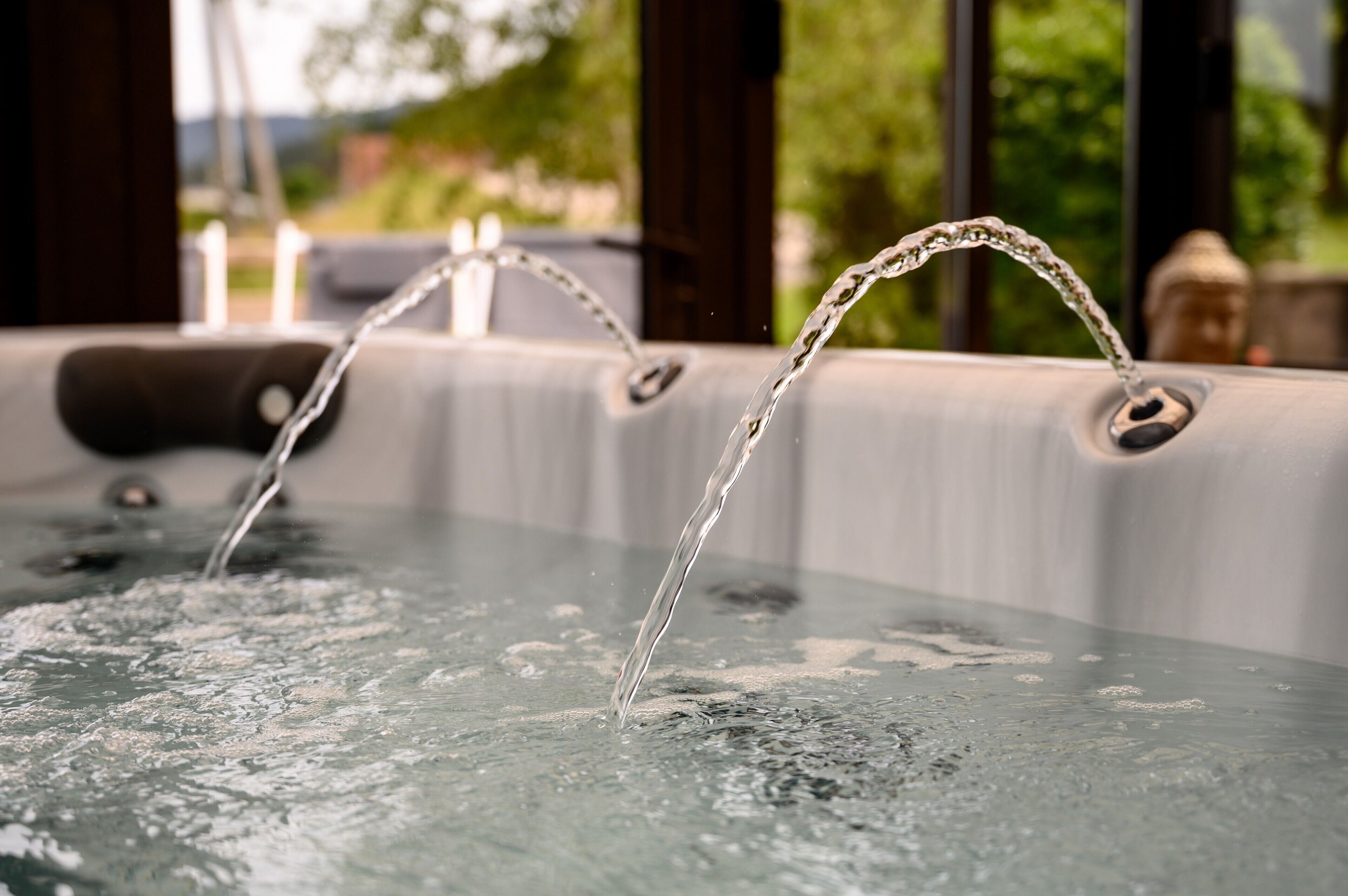 Een hottub met waterstralen, een houten constructie en een onscherpe buitenweergave.
