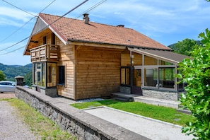 Une cabane en bois avec un toit en pente, un mur de soutènement en pierre et une allée pavée.
