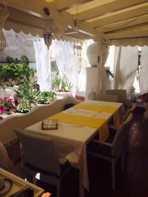 An indoor dining area with tables, chairs, and potted plants.