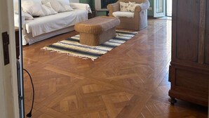 Ein Wohnzimmer mit Sofa, Sessel, Hocker, Kamin und Holzboden.