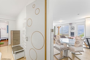 Une chambre moderne comprenant un lit, une armoire, une table à manger avec des chaises et une vue sur l’extérieur, visible à travers une porte vitrée.