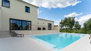 Une maison moderne dotée d’une piscine, de grandes fenêtres et d’un balcon.