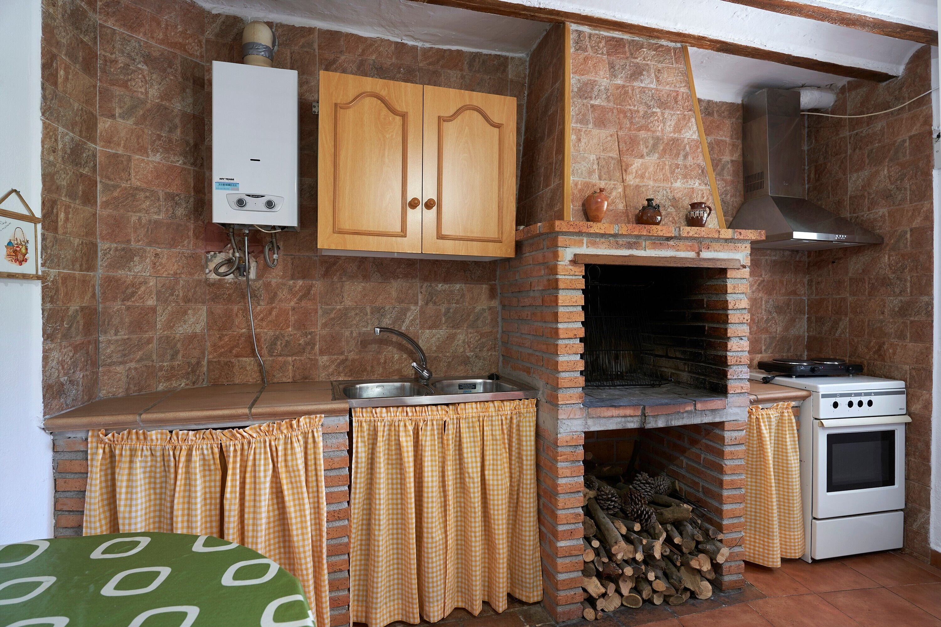 Una cocina con horno empotrado, estufa, pileta y calentador de agua.