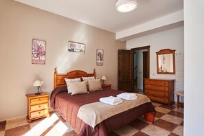 A bedroom with a bed, nightstands, a dresser, and wall art. - Holiday Home 'Alojamiento Rural Puente Honda' with Mountain View, Pool & Wi-Fi (Benatae)