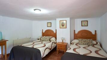 Un dormitorio con dos camas, una mesita de noche, un radiador y una lámpara en el techo.