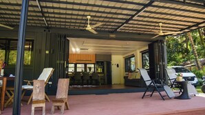 Un espace extérieur abrité comprenant une table à manger et des chaises, un canapé et une petite table sur laquelle est posé un ananas.