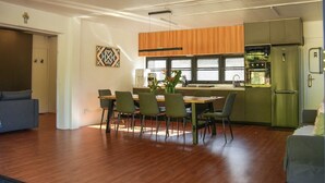 Une cuisine moderne avec des meubles en bois, un réfrigérateur vert et un coin repas comprenant une table et des chaises.