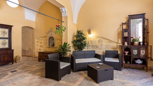 Un intérieur chaleureux avec des meubles en osier, un mur en pierre et un meuble en bois agrémenté d’objets décoratifs.