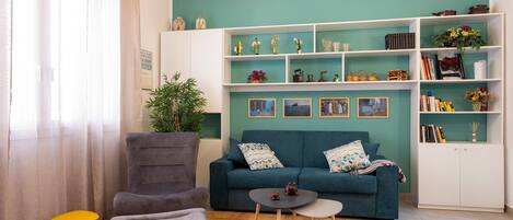 Una sala de estar con sofá, sillón, mesita y estantería.