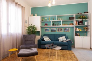 Un salon comprenant un canapé, un fauteuil, une petite table et une bibliothèque.