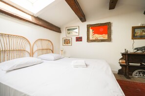 A room with a bed, two wooden headboards, a skylight, and wall-mounted artwork.