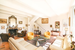 A spacious living room with a fireplace, two armchairs, a sofa, a glass coffee table, and a staircase leading to another level. - Villa 'Bastide Les Oréades' with Private Pool, Wi-Fi and Air Conditioning (Marseille)