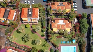 Vista aérea de un barrio residencial con casas, una piscina y un césped bien cuidado.