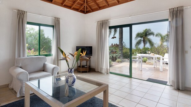 Un salón moderno con sofá, mesa de centro, televisor y vistas al exterior.