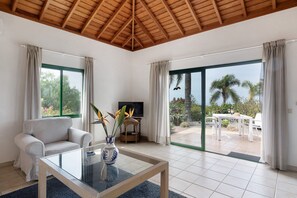 A modern living room with a sofa, a coffee table, a TV, and a view of the outdoors.