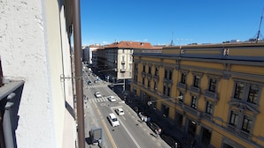 Vista d'un carrer des d'un balcó, amb edificis, vehicles i vianants.
