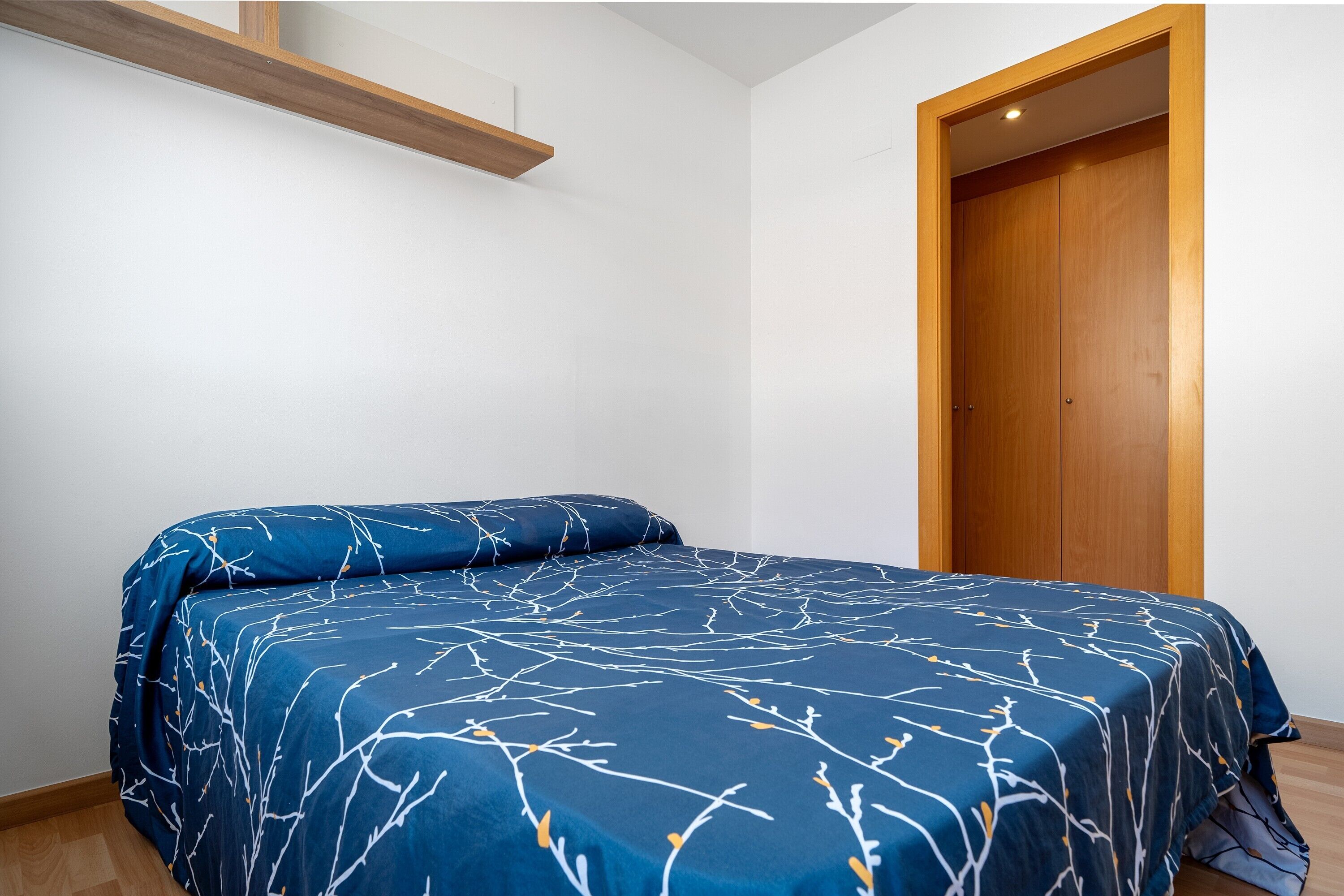 A bedroom with a bed, a wooden door, and a white wall.