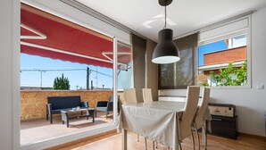 Un espace repas avec une table et des chaises, un auvent rouge et une vue sur l’extérieur.