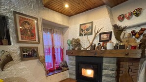 A cozy living room with a fireplace, wooden beams, and a yellow sofa. - Holiday Home "Casa Fiore" with Mountain View, Private Garden & Wi-Fi (Borgo Capanne)