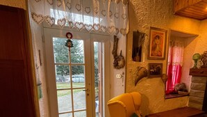 A room with a yellow armchair, a wooden cabinet, a tiled floor, and a door with a white curtain. - Holiday Home "Casa Fiore" with Mountain View, Private Garden & Wi-Fi (Borgo Capanne)