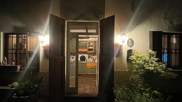 A nighttime view of a building entrance with a lit pathway leading to a door, surrounded by potted plants and a small garden area. - Holiday Home "Casa Fiore" with Mountain View, Private Garden & Wi-Fi (Borgo Capanne)