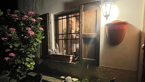 A dimly lit outdoor area with a bench, potted plants, and a window with bars. - Holiday Home "Casa Fiore" with Mountain View, Private Garden & Wi-Fi (Borgo Capanne)