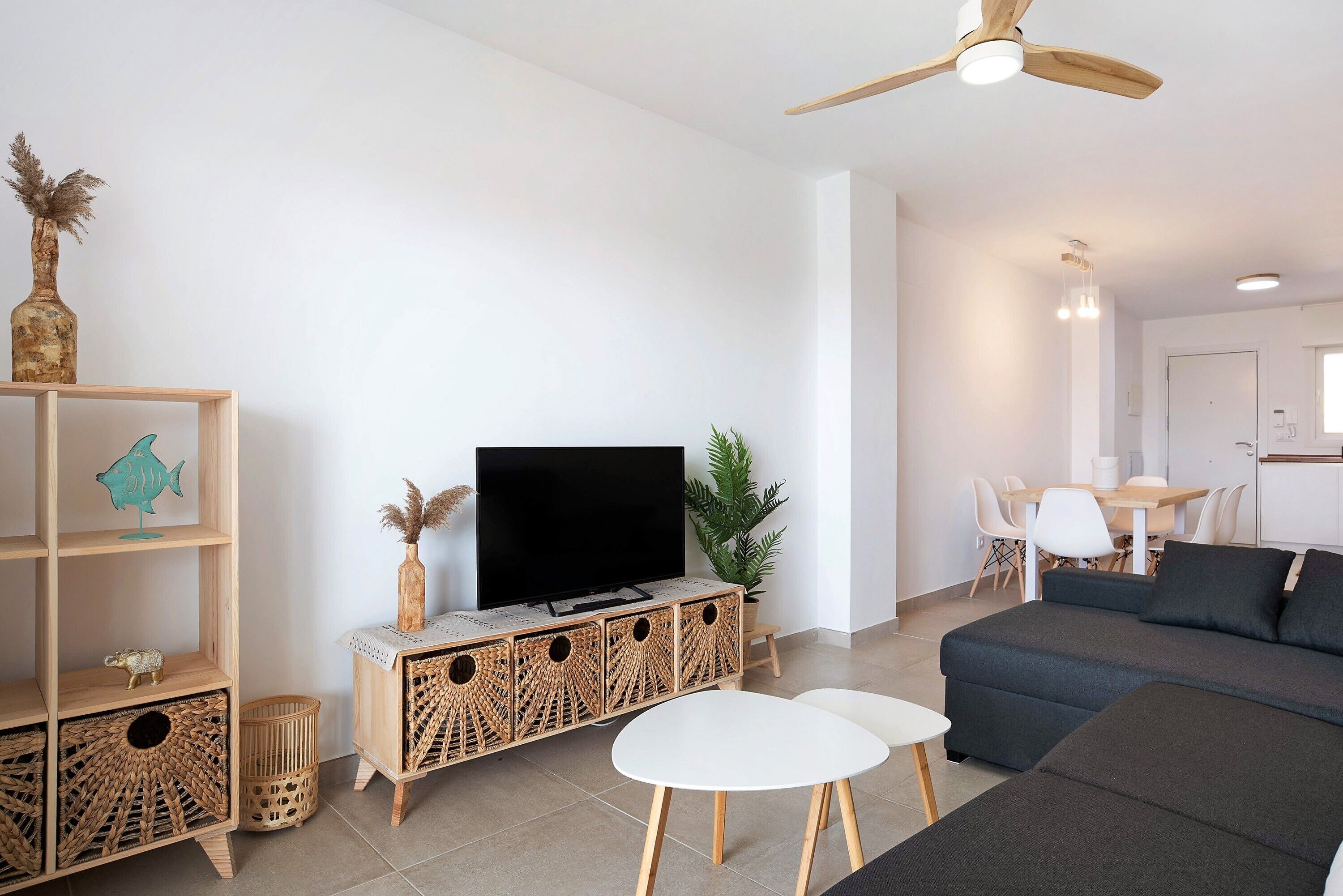 A living room with a sofa, TV, wooden shelves, and a dining area.