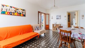 Una stanza con un divano, un tavolo da pranzo, una sedia, un pavimento decorato, un quadro e una porta che dà su un'altra stanza.