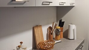 Una cucina con mobili bianchi, un piano di lavoro grigio e diversi utensili da cucina.