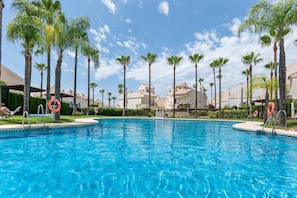 A swimming pool surrounded by palm trees and buildings.