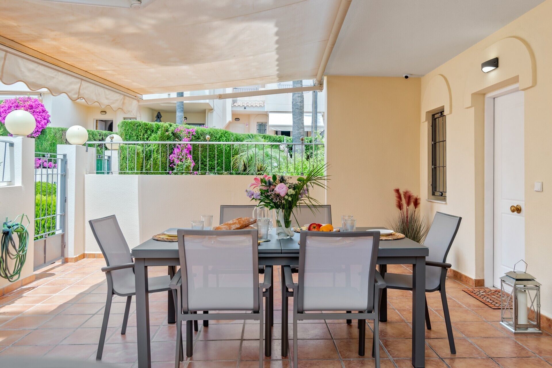 Un comedor con una mesa dispuesta para seis personas, rodeada de sillas, y vistas a un jardín exuberante.