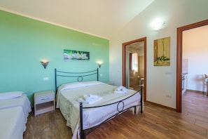 A bedroom with a bed, nightstands, a wooden floor, and artwork on the walls.