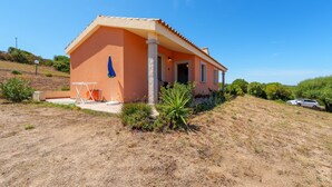 Une maison de plain-pied avec un toit en pente, une véranda et un petit jardin.