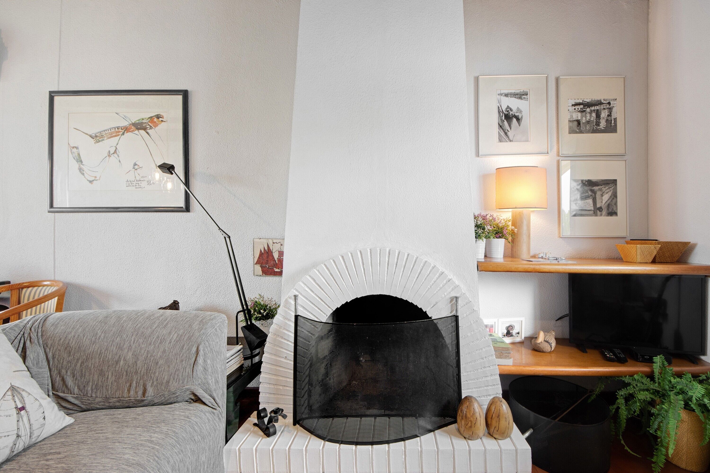 A living room with a fireplace, a sofa, a television, and framed pictures on the wall.