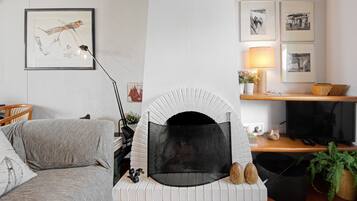 A living room with a fireplace, a sofa, a television, and framed pictures on the wall.