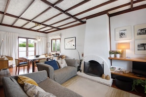 Ein Wohnzimmer mit Kamin, Sofas, einer Essecke und einem Fernseher.