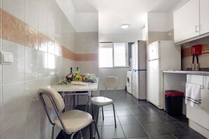 Uma cozinha com área de refeições, máquina de lavar e geladeira.
