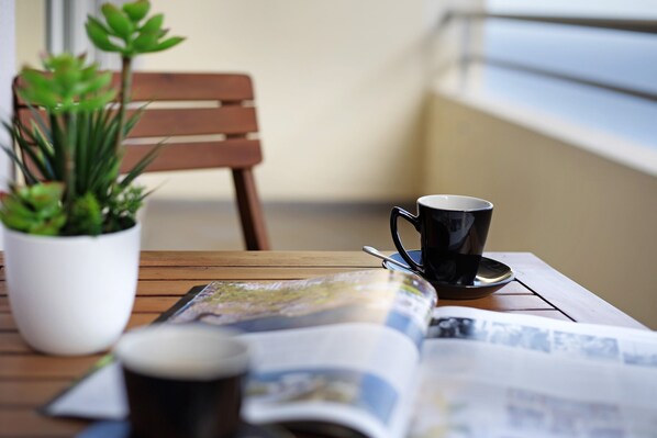 Uma mesa de madeira com uma revista, uma xícara e um vaso de planta.