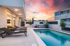 A modern outdoor pool area with lounge chairs, a hot tub, and a view of the sunset. - Apartment Sun Private Pool and Jacuzzi  (Novalja)