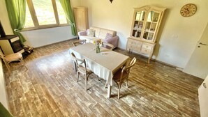 Un rincón comedor acogedor con una mesa y sillas de madera, un sofá, un armario y un reloj en la pared.