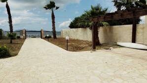 A paved pathway leading to a wooden pergola with a view of the sea. - 4 Bedroom Villa in Marsala (Marsala)