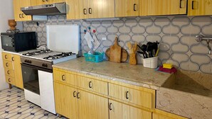 A kitchen with wooden cabinets, a gas stove, a microwave, and a tiled backsplash. - 4 Bedroom Villa in Marsala (Marsala)