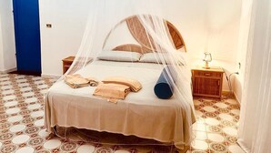 A bed with a canopy, a bedside table with a lamp, and patterned floor tiles. - 4 Bedroom Villa in Marsala (Marsala)