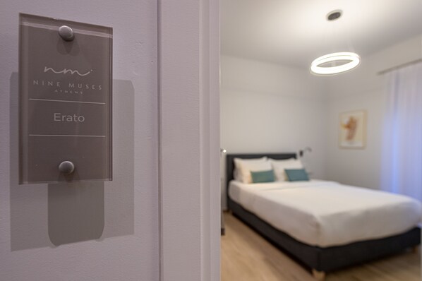 A hotel room with a bed, a nightstand, and a wall-mounted light fixture.
