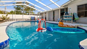 Una piscina interior con tobogán, una piscina inflable pequeña y un aro de baloncesto.