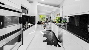 A modern kitchen with sleek cabinetry, a central island, and a black and white patterned floor.